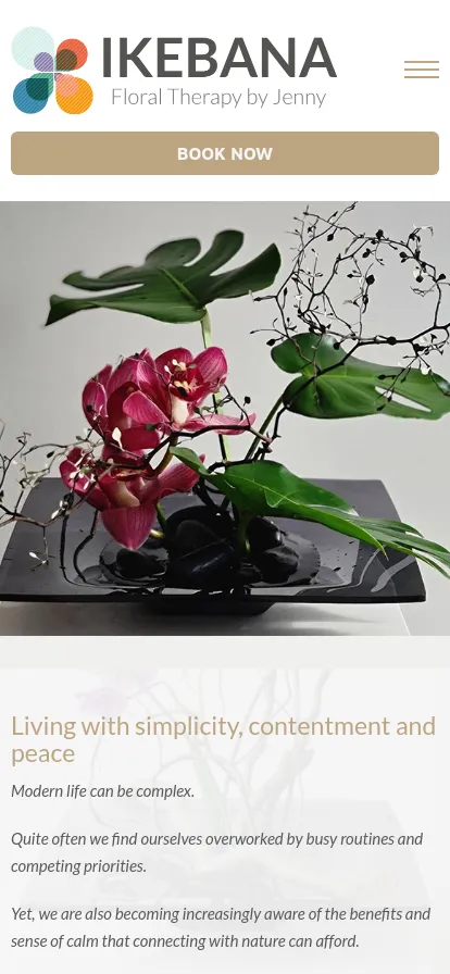 Ikebana floral arrangement with pink orchids and leaves.