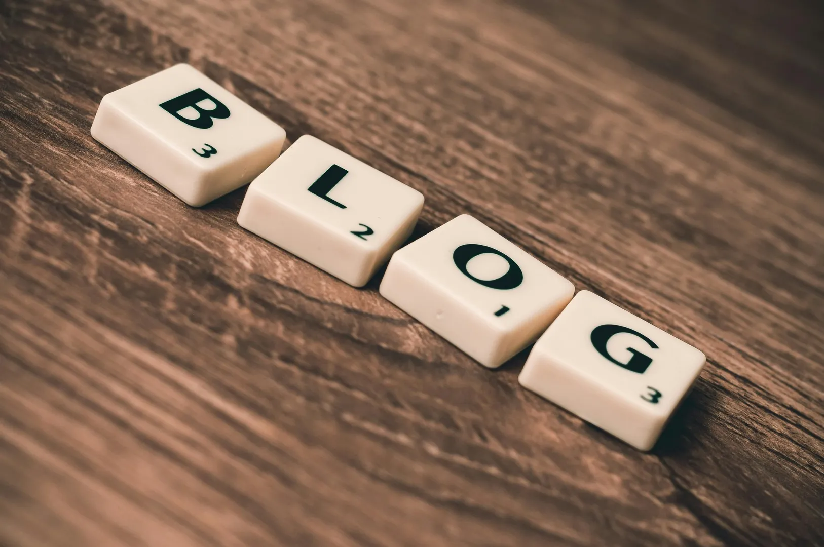 Scrabble tiles spelling 'BLOG' on wooden surface.